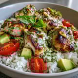 Healthy pesto chicken bowl featuring grilled chicken, spinach, cucumber, and vibrant red onion served for lunch.