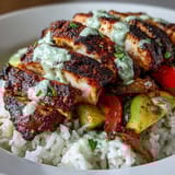 Sizzling Blackened Chicken Bowl resting on white rice, garnished with fresh cilantro and bright lime wedges, perfect for dinner.