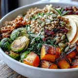 Savory roasted Fall Vegetable Bowl featuring tender squash, crispy Brussels sprouts, and wilted kale on farro, garnished with cranberries and optional feta.