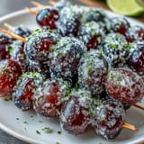 Zesty lime sugar sparkles on icy grapes threaded onto wooden skewers, perfect for summer snacking.