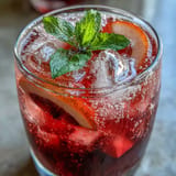 Refreshing Sparkling Hibiscus Mint Lemonade Mocktail poured over ice for enjoyment.
