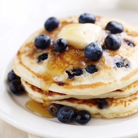 A stack of blueberry pancakes, drizzled with sweet maple syrup, perfect for a cozy morning meal.