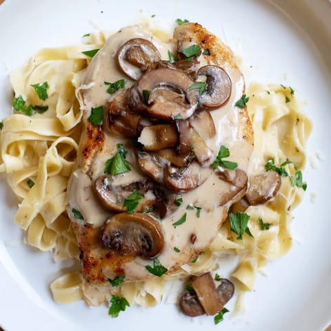 Golden, pan-seared Chicken Marsala coated in a creamy mushroom sauce, served over fettuccine and garnished with fresh parsley.