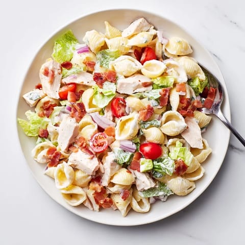 A close-up of BLT Chicken Pasta Salad, featuring pasta shells, romaine lettuce, and diced grilled chicken tossed in mayo.  