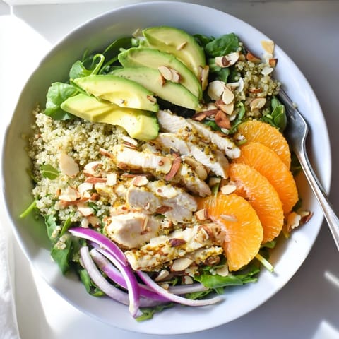 A vibrant Citrus Herb Chicken Salad Bowl with grilled chicken, quinoa, fresh greens, and orange slices in a white bowl.