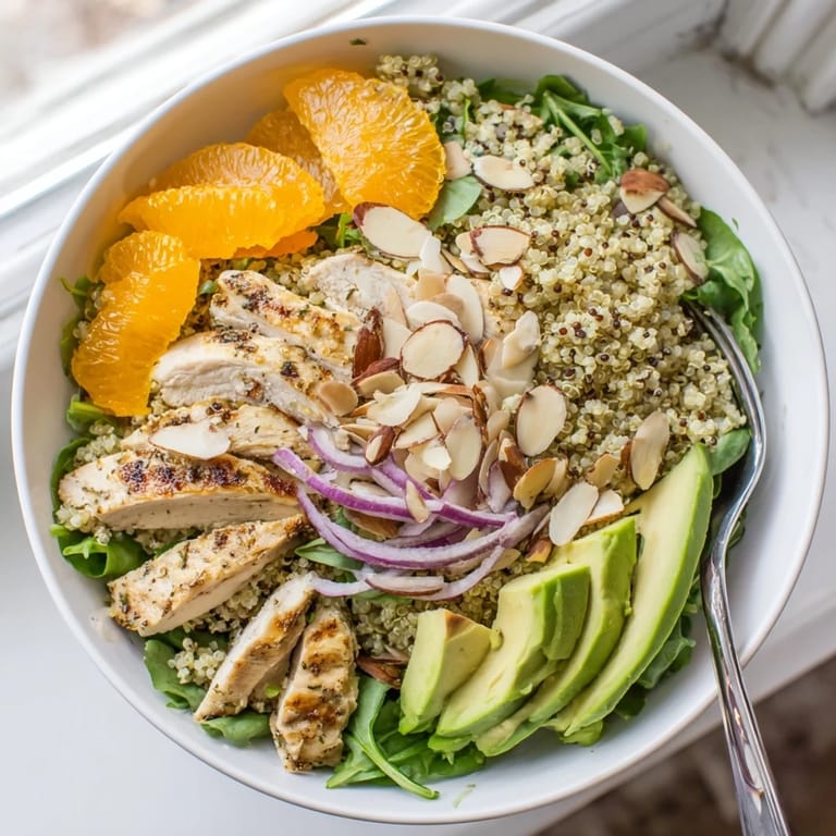 Overhead view of a colorful Citrus Herb Chicken Salad Bowl topped with creamy avocado, red onion, and toasted almonds.