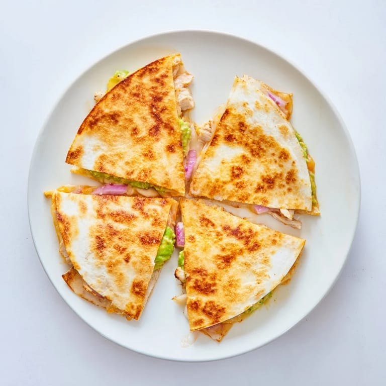 A close-up of a sliced Chicken Avocado Quesadilla showing the juicy chicken and gooey cheese filling.  