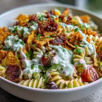 Colorful Taco Pasta Salad with Doritos and Avocado Ranch, topped with crunchy tortilla chips and fresh veggies.