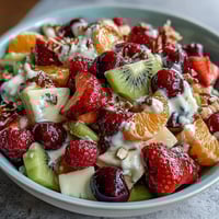 Rainbow fruit table with coconut whipped cream, featuring strawberries, kiwi, blueberries, and oranges arranged in vibrant rows.